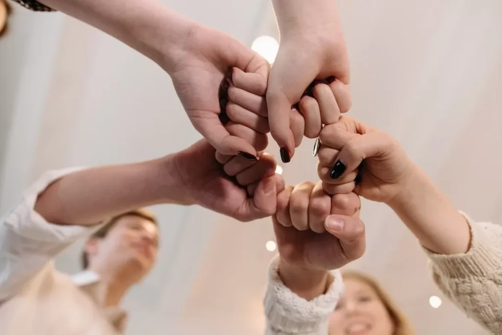 Close-up of a diverse group joining fists in a show of unity and teamwork indoors