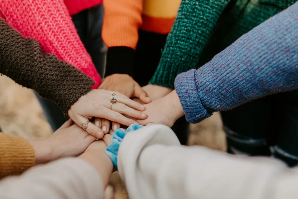 Group stacking hands in colorful sweaters