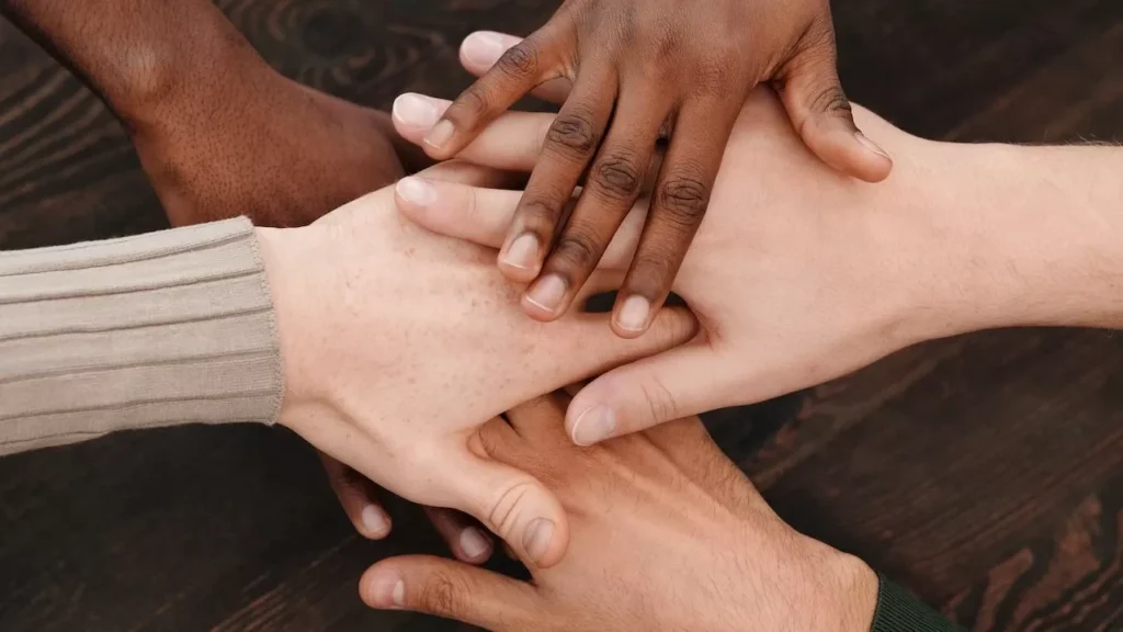 Close-up of diverse hands stacked together on wooden surface symbolizing teamwork and unity