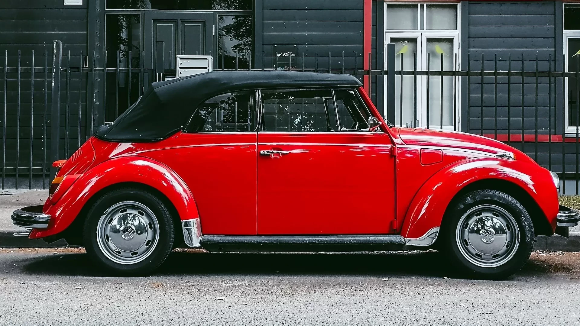 red car parked beside white and gray house