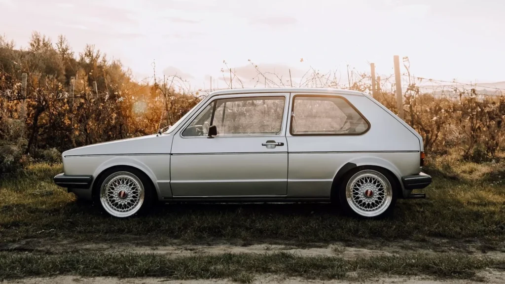 white station wagon on green grass field under white clouds during daytime