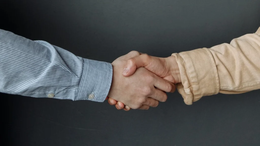A close-up of two adults shaking hands, symbolizing agreement and partnership