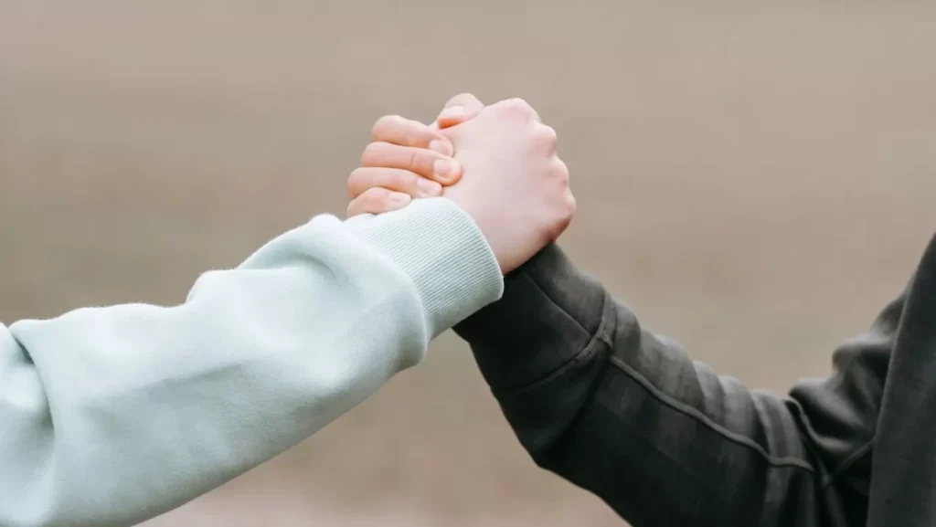 Two adults holding hands in an outdoor park setting, symbolizing trust and connection