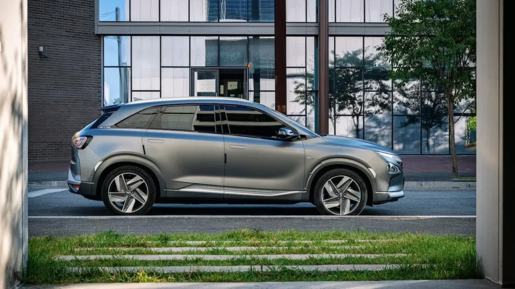 Side view of a sleek gray SUV parked beside a glass building in an urban setting