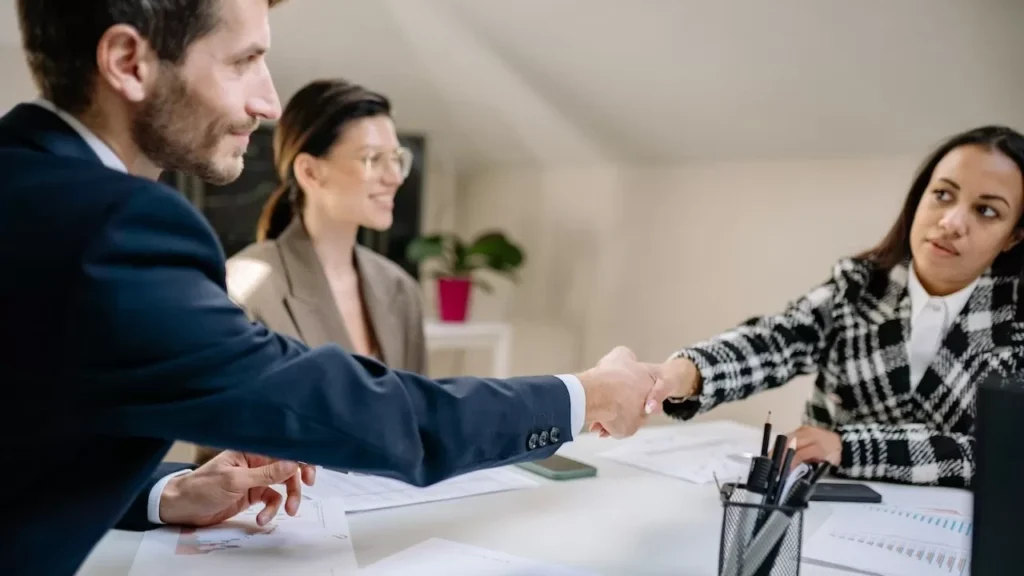 A group of diverse professionals engaged in a business meeting and handshake in a modern office
