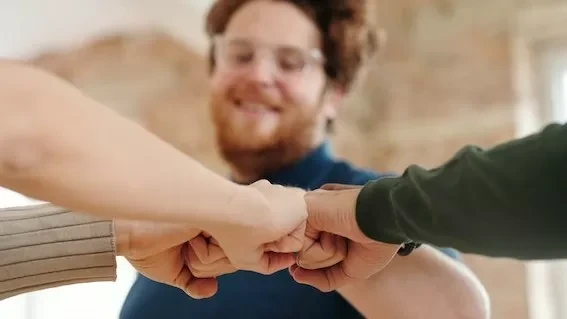 Group of diverse adults showing unity and teamwork with a fist bump indoors