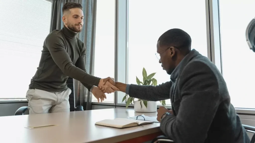 wo businessmen shaking hands in a modern office after a successful meeting or interview