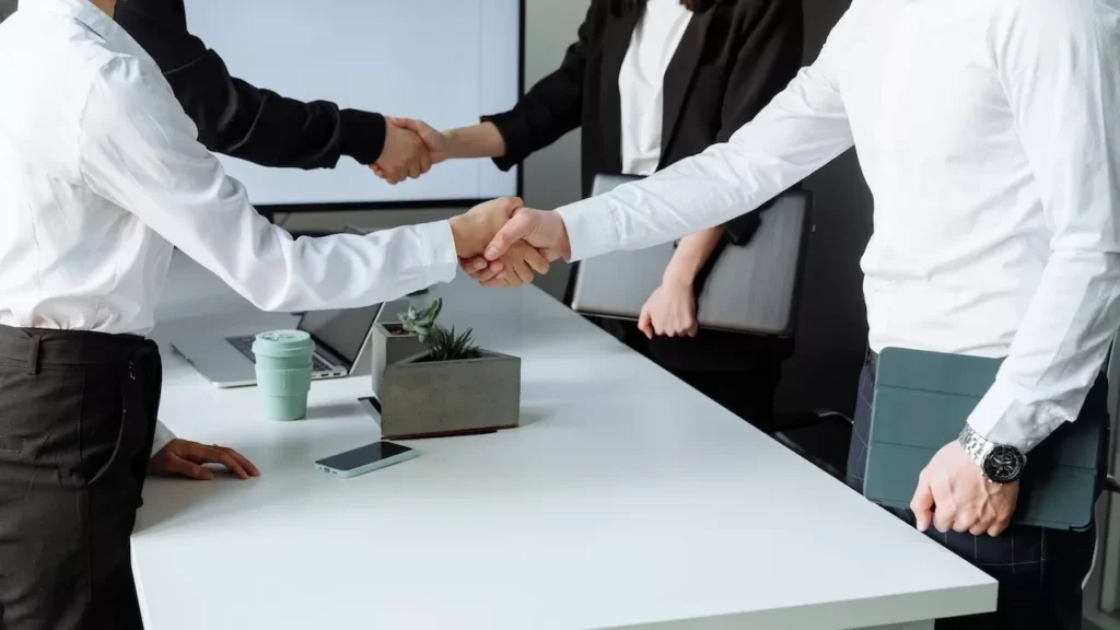 Business professionals shaking hands over a deal at a modern office table