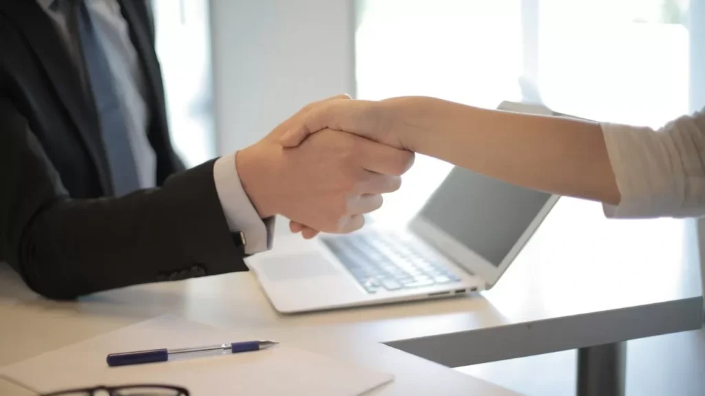 Close-up of a professional handshake over a laptop during a business meeting in an office