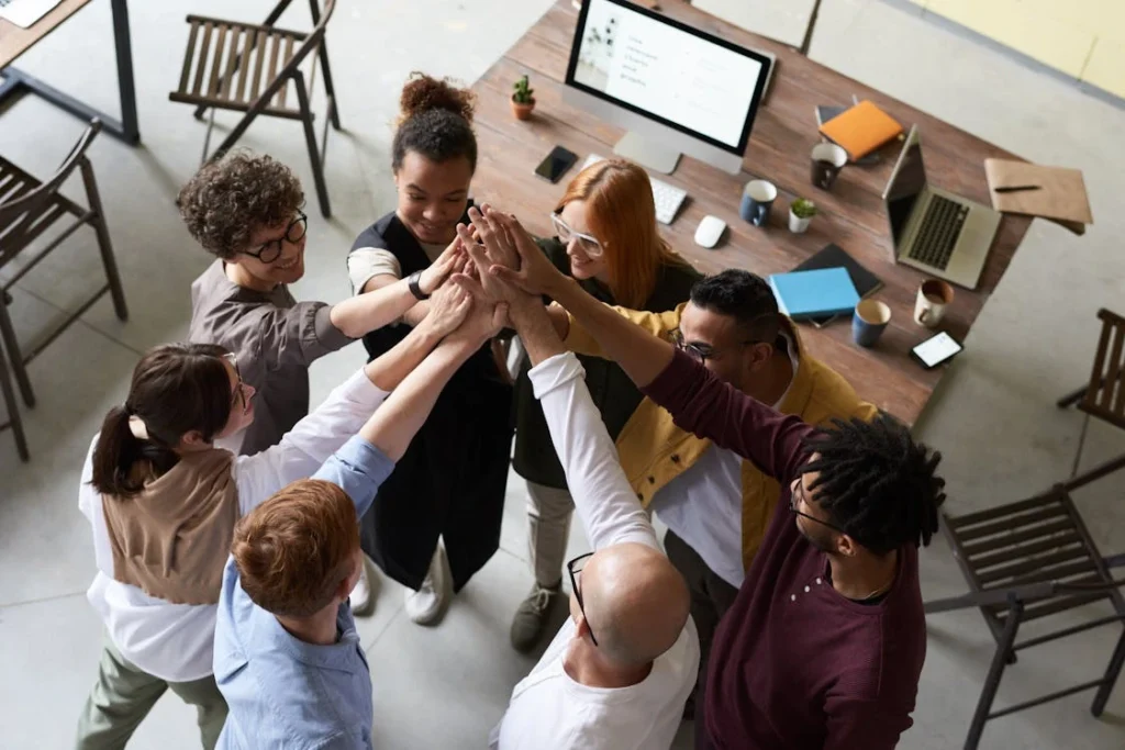 A diverse group of colleagues giving a high five during a corporate meeting indoors