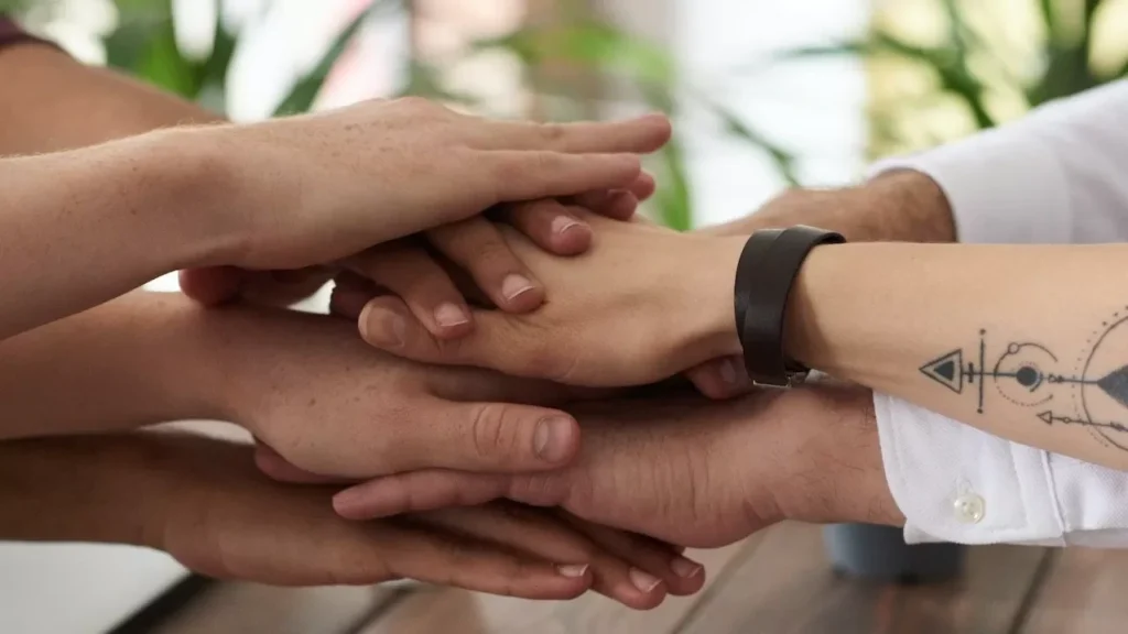 Hands from a diverse team stack on a table symbolizing unity and teamwork in a modern office setting