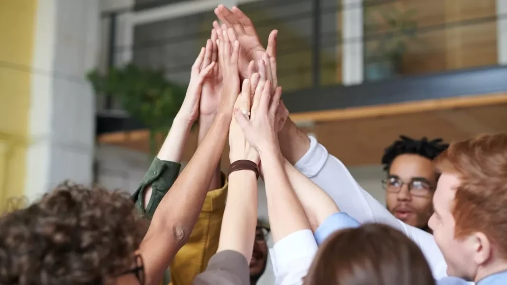 A group of diverse professionals celebrating teamwork with a high-five indoors
