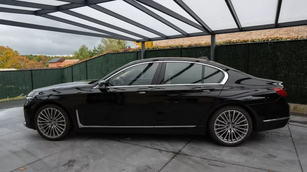Sleek black luxury car parked under a modern glass-roofed garage