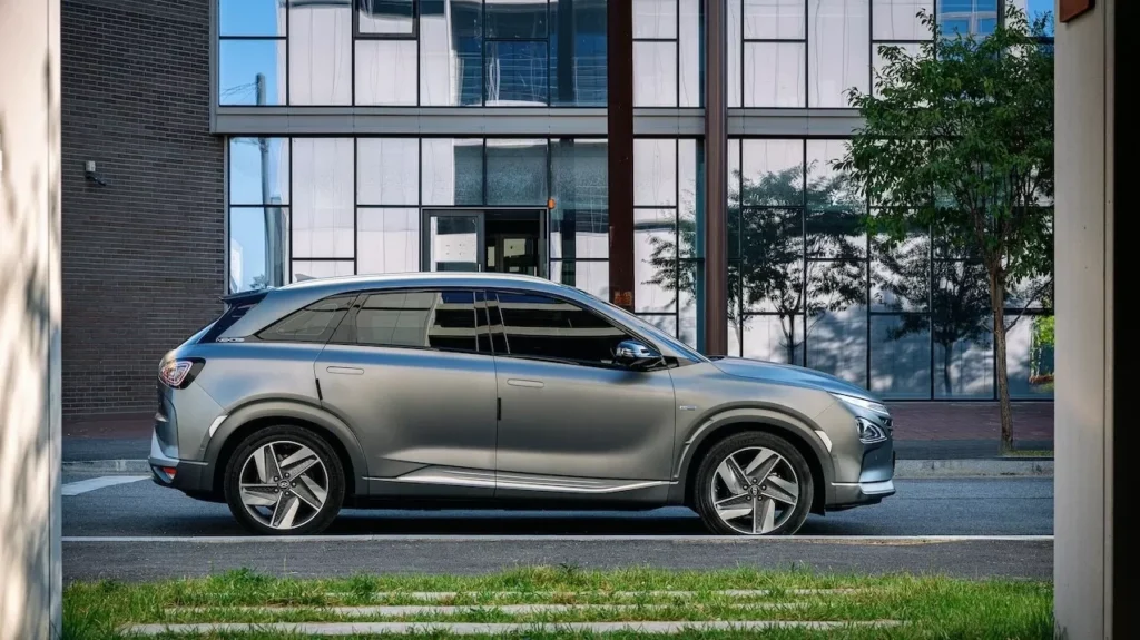 Side view of a sleek gray SUV parked beside a glass building in an urban setting