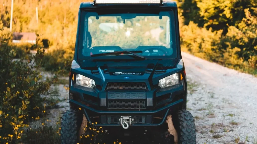 Front view of a parked ATV on a countryside path with mountains and trees