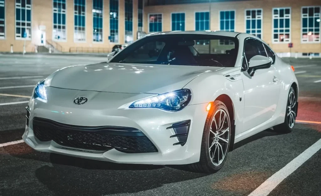 A sleek white coupe illuminated against the backdrop of a city nightscape