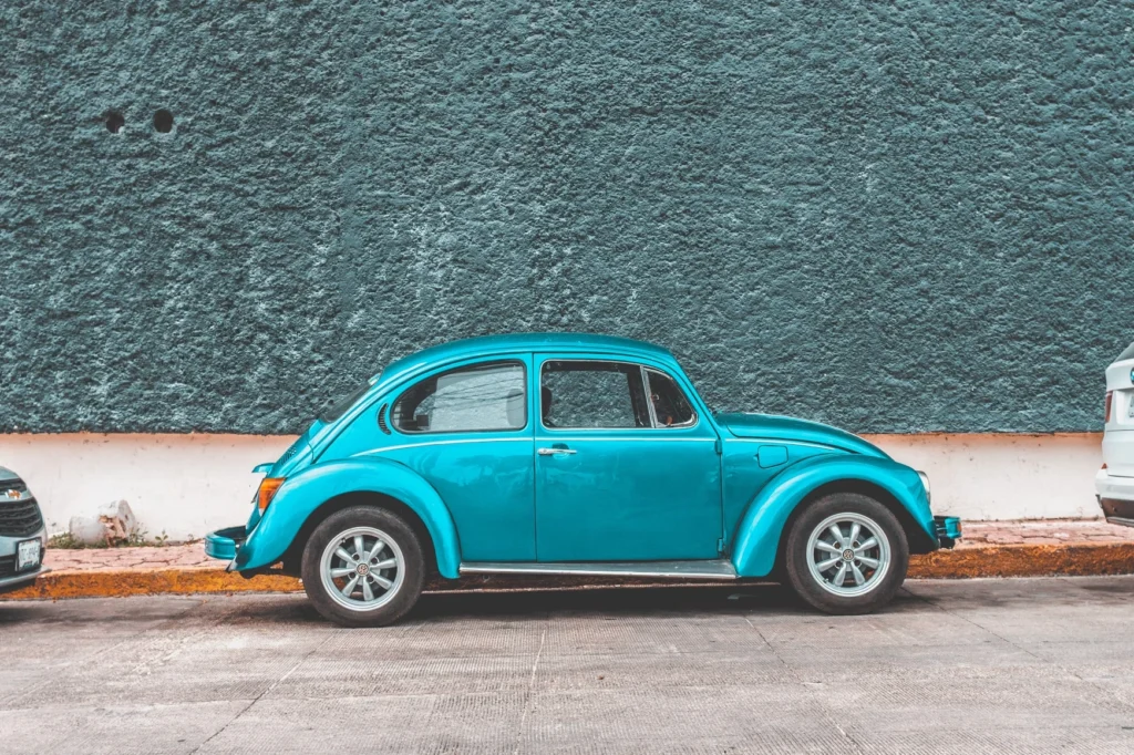 Teal Volkswagen Beetle car parked beside sidewalk