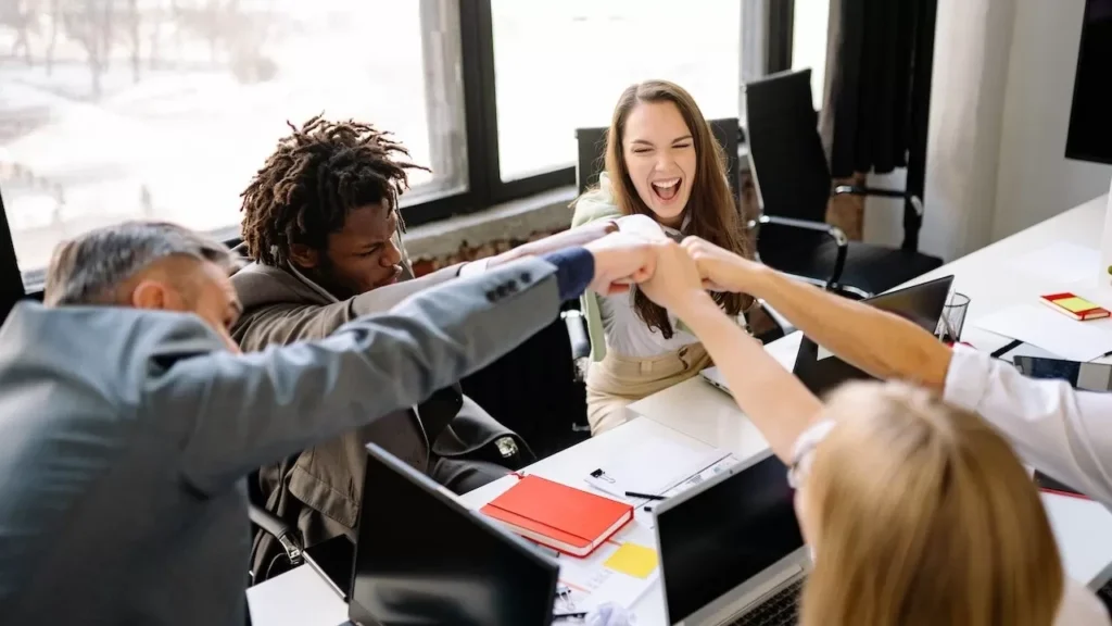 A diverse group of professionals celebrate a successful meeting with a fist bump