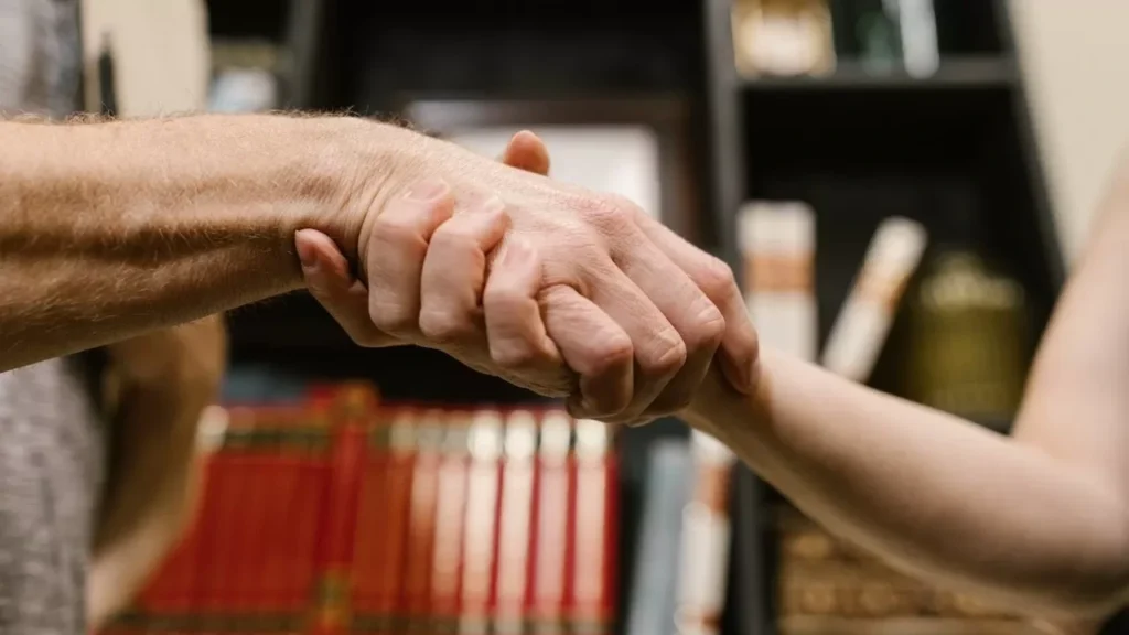 A close-up handshake symbolizing agreement, friendship, and trust inside a library