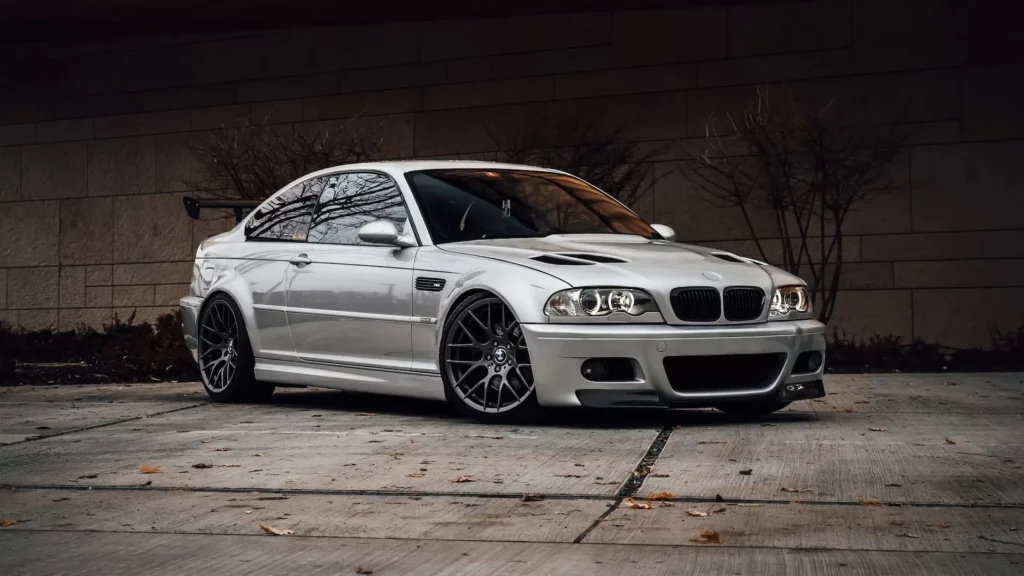 White BMW m 3 coupe parked beside orange wall